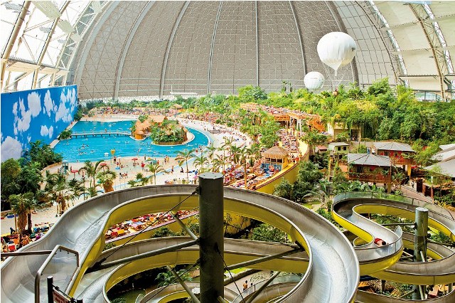 hese are the incredible images of a tropical island paradise INSIDE a building so big could easily fit eight football pitches. A sandy beach, spa, waterfall, whirlpools and water slides are just a few of the attractions inside the old airship hanger. The indoor tropical island, located in Brandenburg, Germany, boasts an air temperature of 26 degrees, with water being 28C in the Tropical Sea and 32 C in the Bali Lagoon. Inside the paradise also host to the worlds biggest indoor rainforest, which features over 50,000 plants and spans over a 10,000 metre square area
