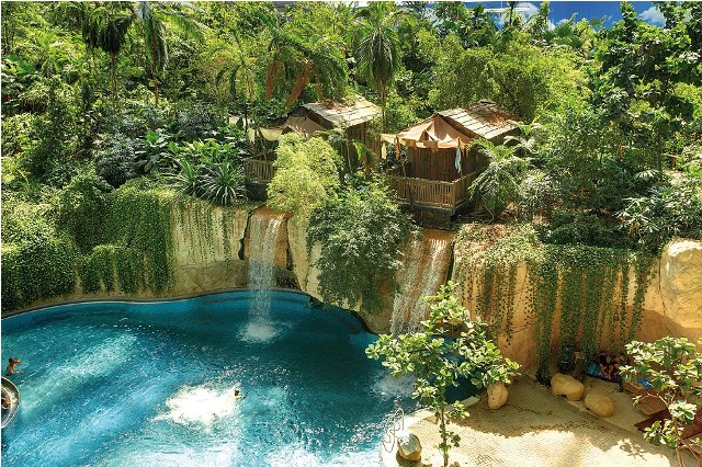 hese are the incredible images of a tropical island paradise INSIDE a building so big could easily fit eight football pitches. A sandy beach, spa, waterfall, whirlpools and water slides are just a few of the attractions inside the old airship hanger. The indoor tropical island, located in Brandenburg, Germany, boasts an air temperature of 26 degrees, with water being 28C in the Tropical Sea and 32 C in the Bali Lagoon. Inside the paradise also host to the worlds biggest indoor rainforest, which features over 50,000 plants and spans over a 10,000 metre square area