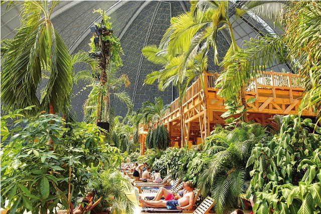 hese are the incredible images of a tropical island paradise INSIDE a building so big could easily fit eight football pitches. A sandy beach, spa, waterfall, whirlpools and water slides are just a few of the attractions inside the old airship hanger. The indoor tropical island, located in Brandenburg, Germany, boasts an air temperature of 26 degrees, with water being 28C in the Tropical Sea and 32 C in the Bali Lagoon. Inside the paradise also host to the worlds biggest indoor rainforest, which features over 50,000 plants and spans over a 10,000 metre square area
