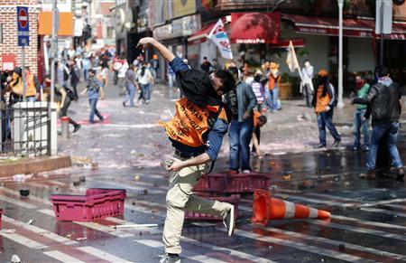 A May Day protester throws a stone at riot police as he and others try to break through barricades to reach the city's main square in central Istanbul