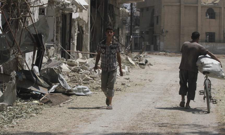 Residents walk in Jobar, a suburb of Damascus, which activists claim has been undergoing violent clashes between forces loyal to Syria's President Bashar al-Assad and rebel fighters