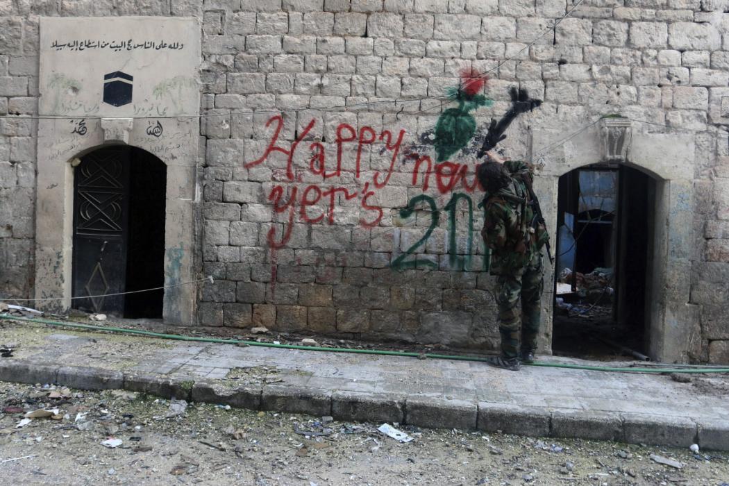 A Free Syrian Army fighter sprays graffiti on a wall prior to the new year in Aleppo