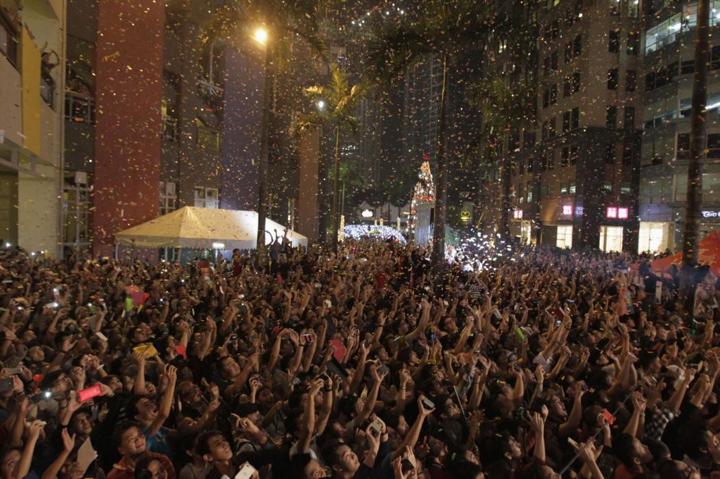 Confetti pours down to the revelry as they watch fireworks lights the sky during the New Year celebrations  in Manila