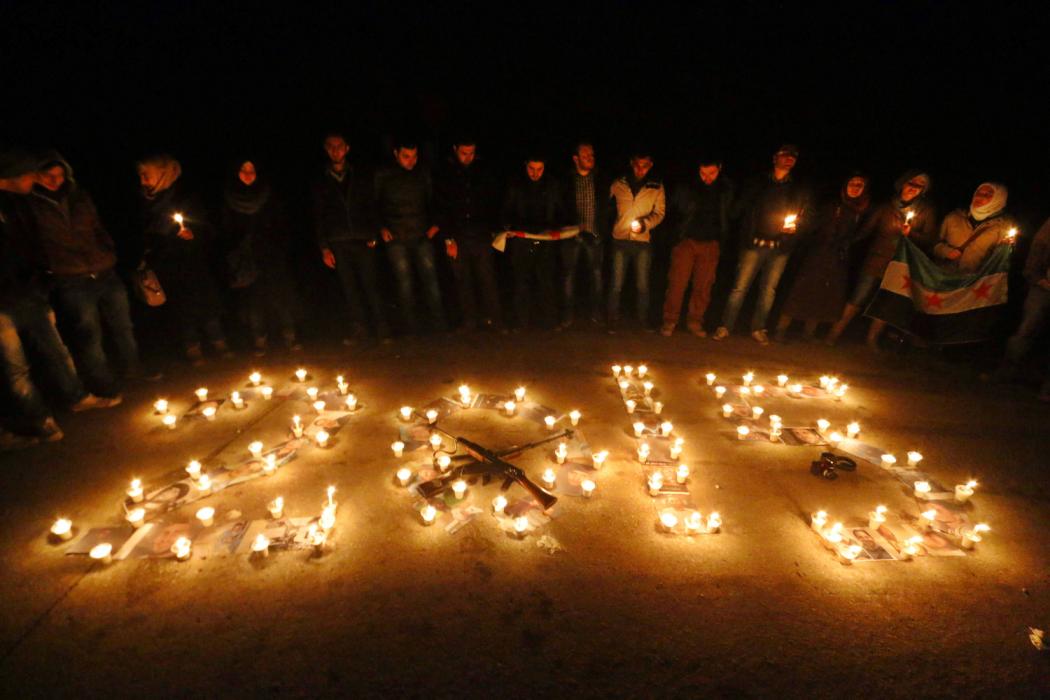 Activists stand over pictures of war victims under candles in a new year event in Salah al-Din neighbourhood in central Aleppo