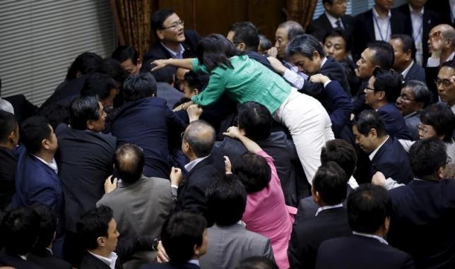 Opposition Democratic Party of Japan lawmaker Hiroe Makiyama (green) climbs over other lawmakers who are guarding Yoshitada Konoike, chairman of the upper house special committee on security, before a vote at an upper house special committee session on security-related legislation at the parliament in Tokyo, Japan, September 17, 2015.   REUTERS/Toru Hanai