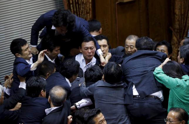 Opposition Democratic Party of Japan lawmaker Konishi climbs over other lawmakers who are guarding Konoike, chairman of the upper house special committee on security, at the parliament in Tokyo