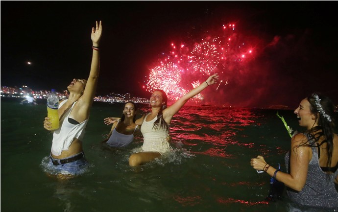 RIO DE JANEIRO, BRAZIL - JANUARY 01:  Revelers celebrate as fireworks explode during New Year's  festivities on Copacabana Beach on January 1, 2015 in Rio de Janeiro, Brazil. Up to 2 million revelers were expected on Copacabana Beach to watch the annual New Year's fireworks display which this year coincided with the start of the city's 450th anniversary celebrations.  (Photo by Mario Tama/Getty Images)